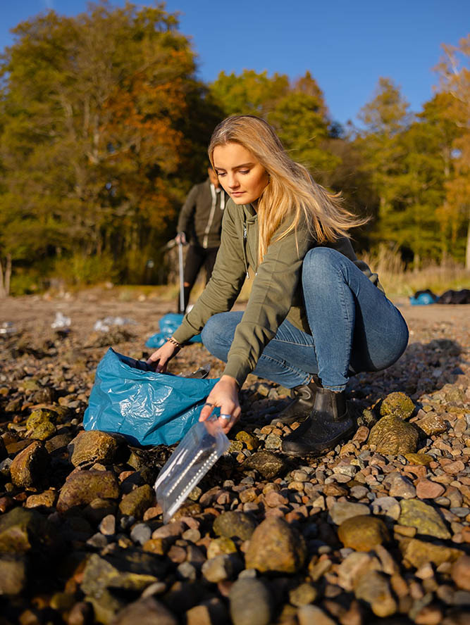 young-woman-picking-up-plastic-at-rocky-beach-2022-12-16-09-53-34-utc-1.jpg